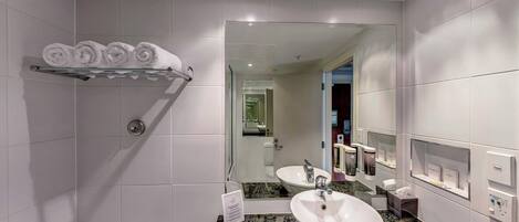 Ein modernes Badezimmer mit Waschbecken, Spiegel, Handtuchhalter und Toilettenartikeln.