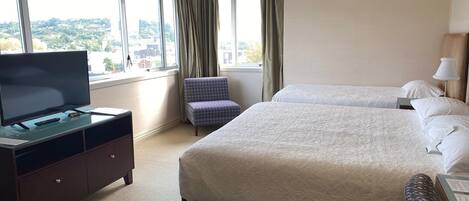 A hotel room with two beds, a TV, a desk, and a chair.