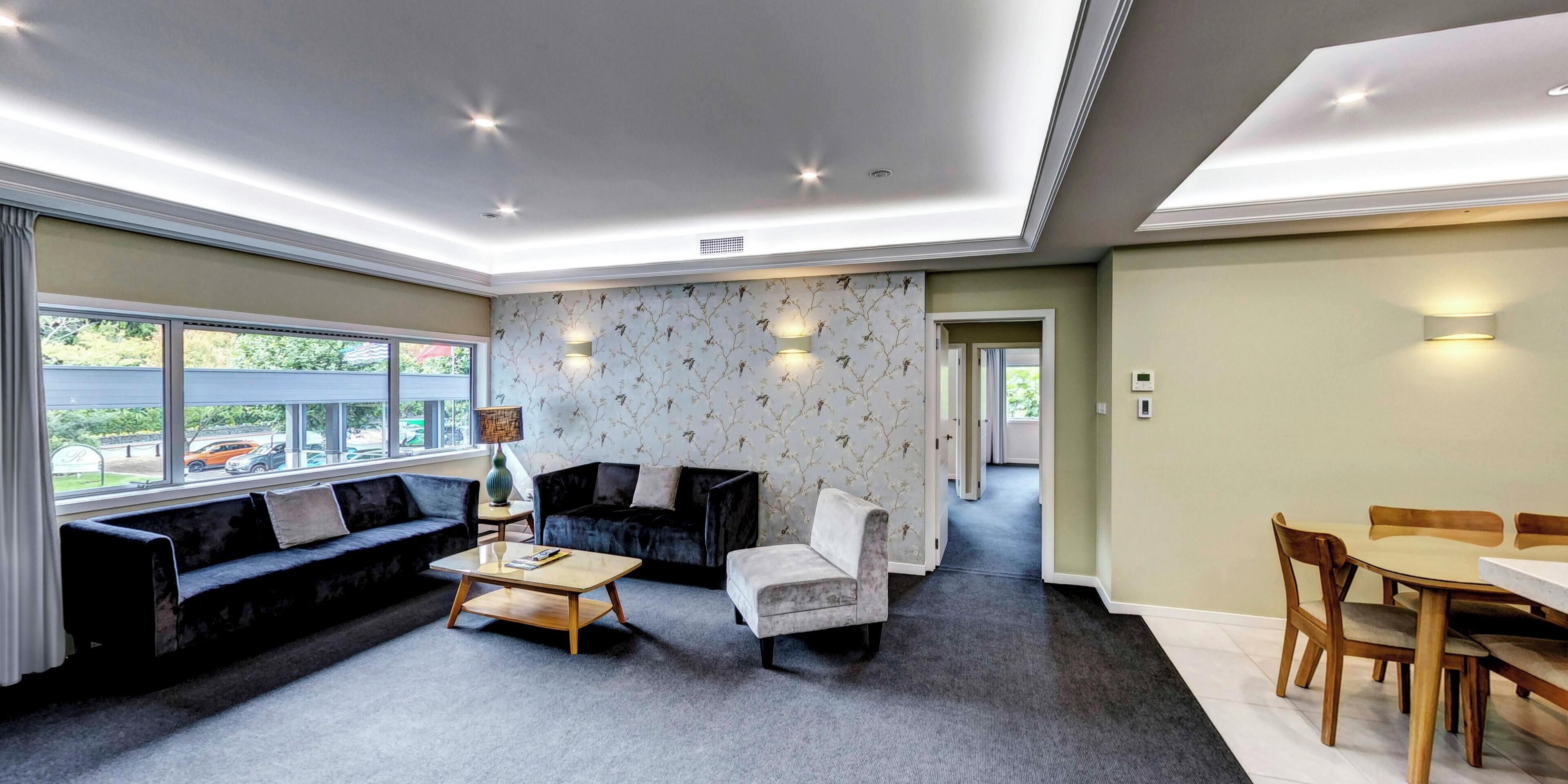 A modern living room with a sofa, armchair, coffee table, and dining table.
