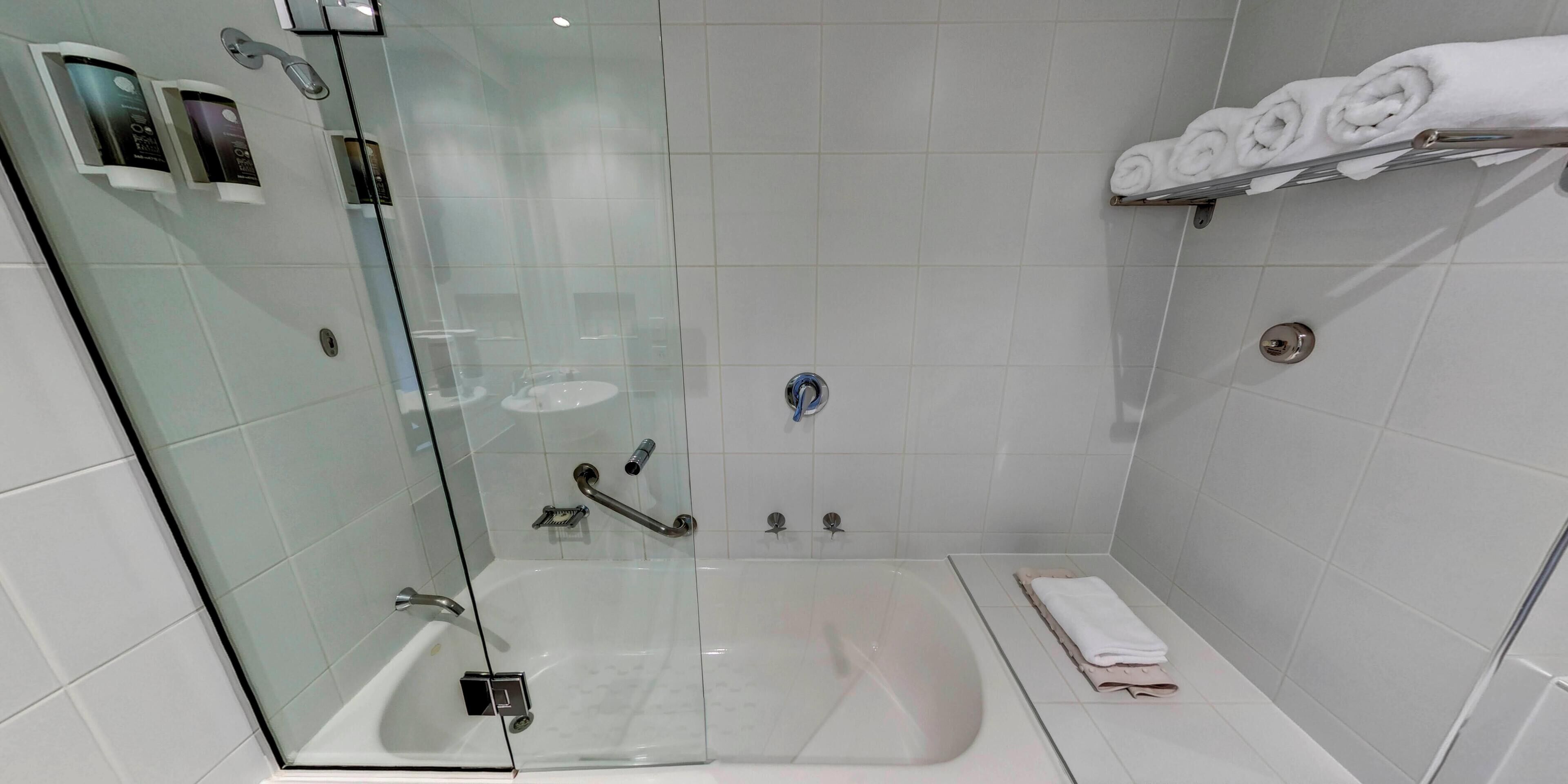 Une salle de bain moderne avec une douche à parois de verre, une baignoire et un meuble-lavabo doté d’un porte-serviettes.