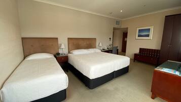 Una habitación de hotel con dos camas, un escritorio, una silla y un armario.