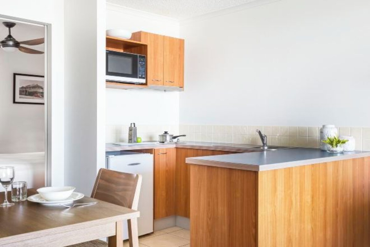 Una cocina moderna con armarios de madera, microondas y una pequeña isla.