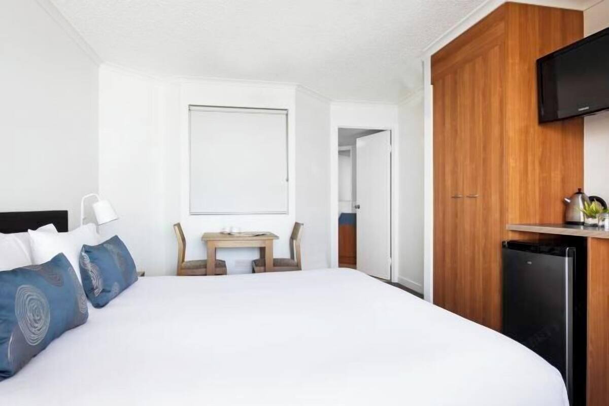 Une chambre d’hôtel équipée d’un lit, d’un bureau, d’une télévision et d’une armoire.