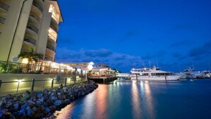 Un hotel frente al agua con un edificio grande, un muelle y varias embarcaciones.