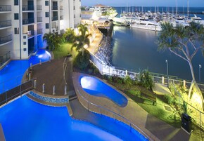Una marina con barcos, piscina y un edificio con balcones.