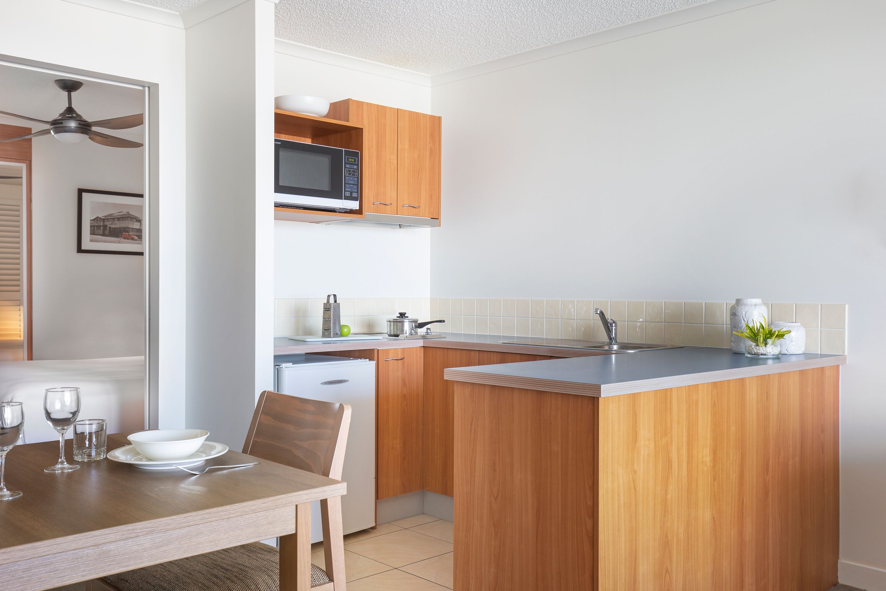 A compact kitchen with wooden cabinets, a microwave, and a sink.