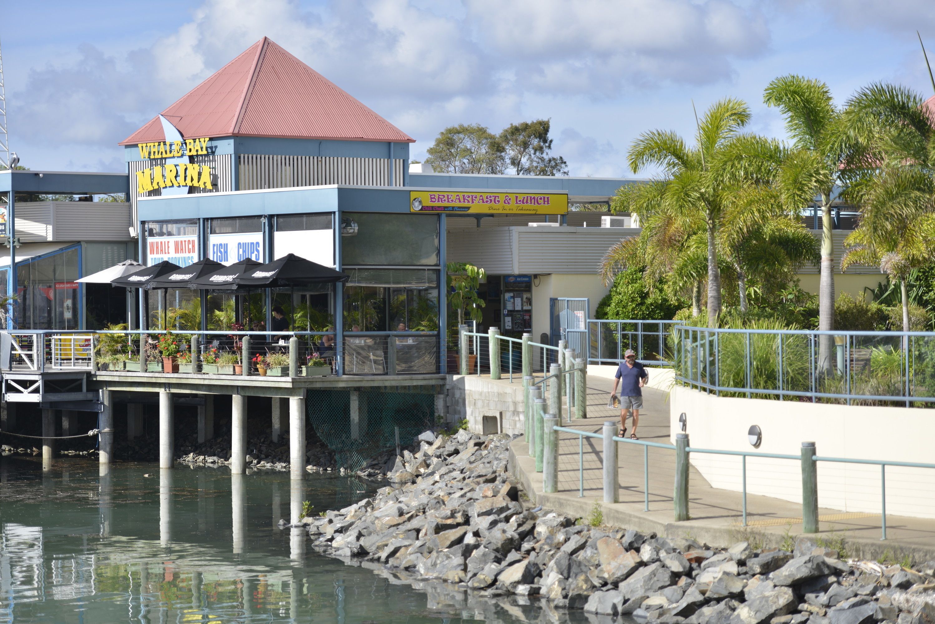 A waterfront restaurant with a sign for 'Whale Bay Marina' and 'Breakfast & Lunch'.