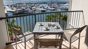 Un balcón con una mesa dispuesta para el té, con vistas a un puerto deportivo lleno de barcos.