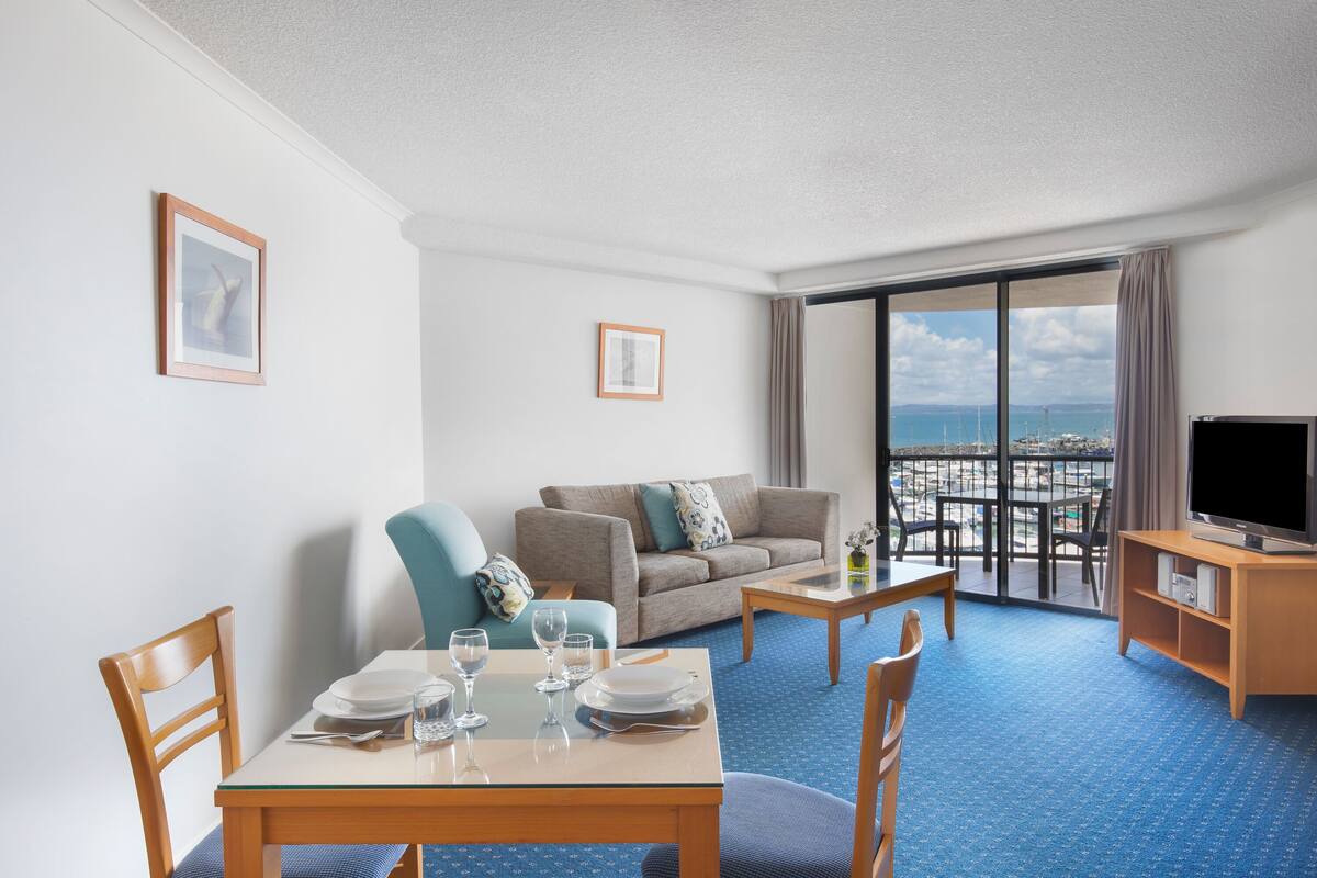 Une chambre d’hôtel comprenant un coin repas, un canapé, une télévision et un balcon avec vue.