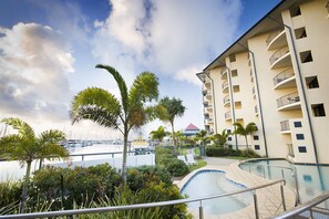 Un hôtel doté d’une piscine, de palmiers et, au loin, d’un port de plaisance.