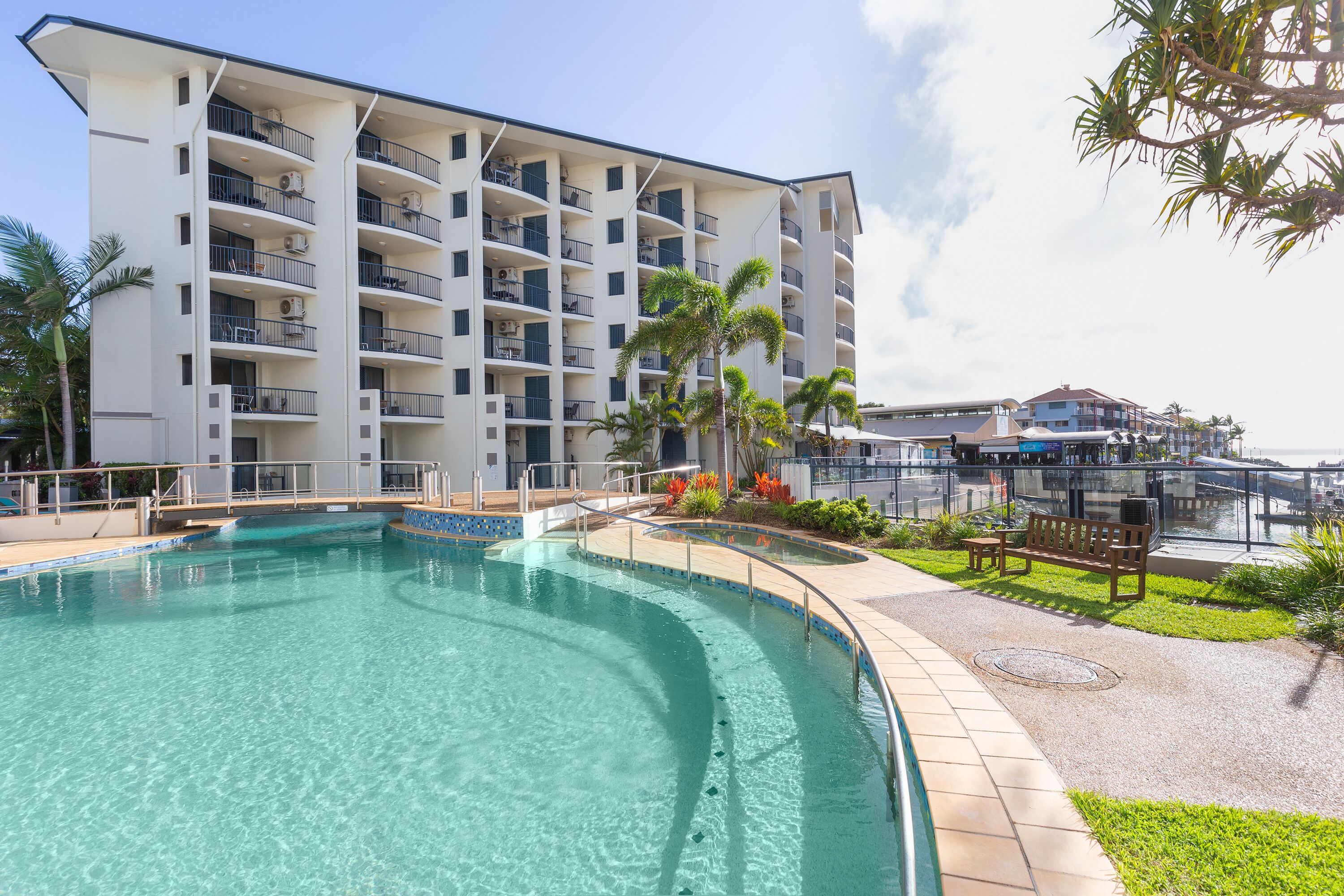 Un hotel con piscina, varios balcones y vistas al puerto deportivo.