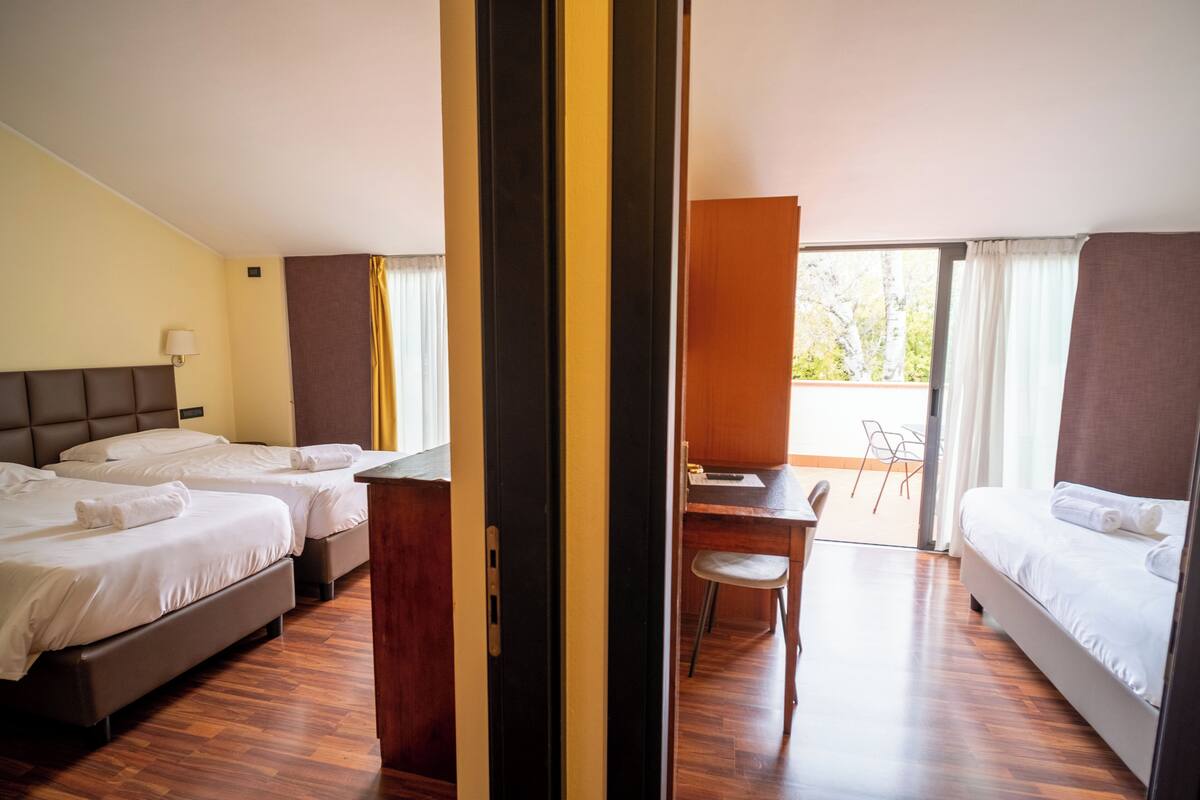 A hotel room with two beds, a desk, and a chair.
