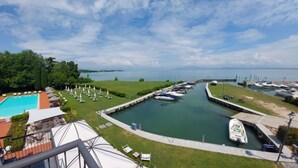Un port de plaisance avec des bateaux amarrés, une piscine et un espace verdoyant équipé de chaises longues.