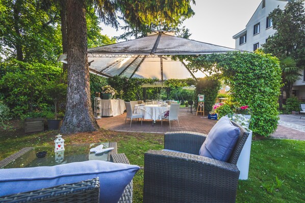 Relax in the shaded patio area with comfortable seating and lush greenery.