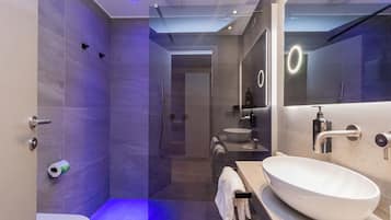 Un baño moderno con un espejo grande, un lavamanos blanco y una zona de ducha.