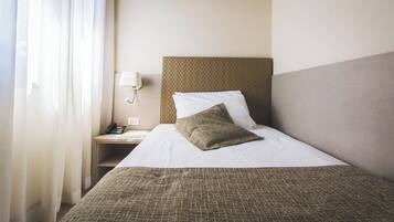 A hotel room with a bed, a bedside table with a lamp, and a phone.