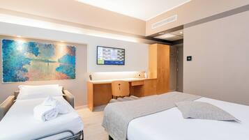 A hotel room with two beds, a desk, a large abstract painting, and a digital clock on the wall.