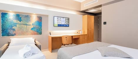 Een hotelkamer met twee bedden, een bureau, een groot abstract schilderij en een digitale klok aan de muur.