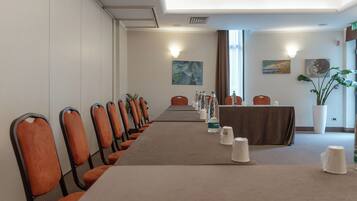 Una sala conferenze con un lungo tavolo, sedie arancioni e una tovaglia marrone.