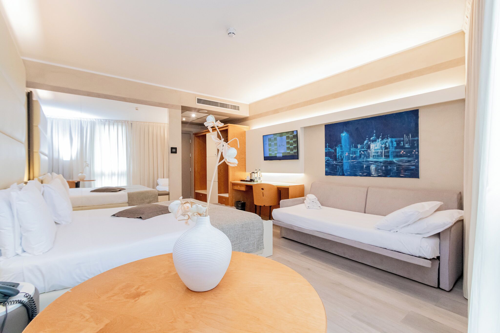Una habitación de hotel moderna con una cama grande, un sofá, un escritorio y un televisor.