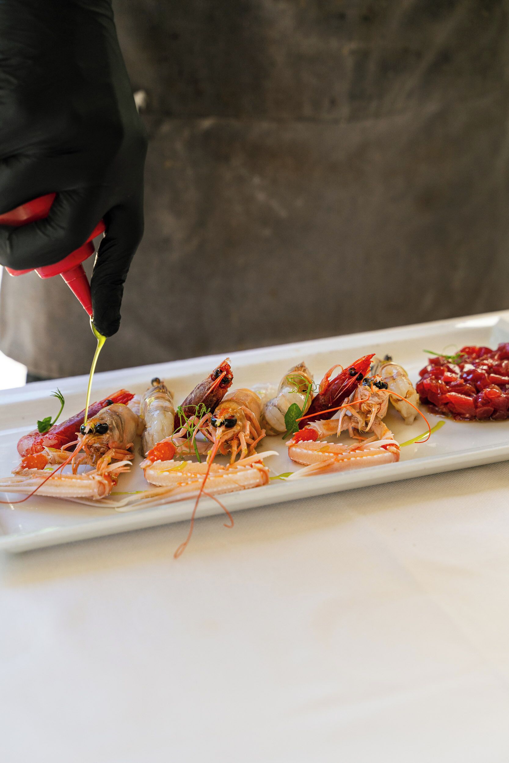 Un chef preparando un plato de mariscos con camarones y otros ingredientes sobre un plato blanco.