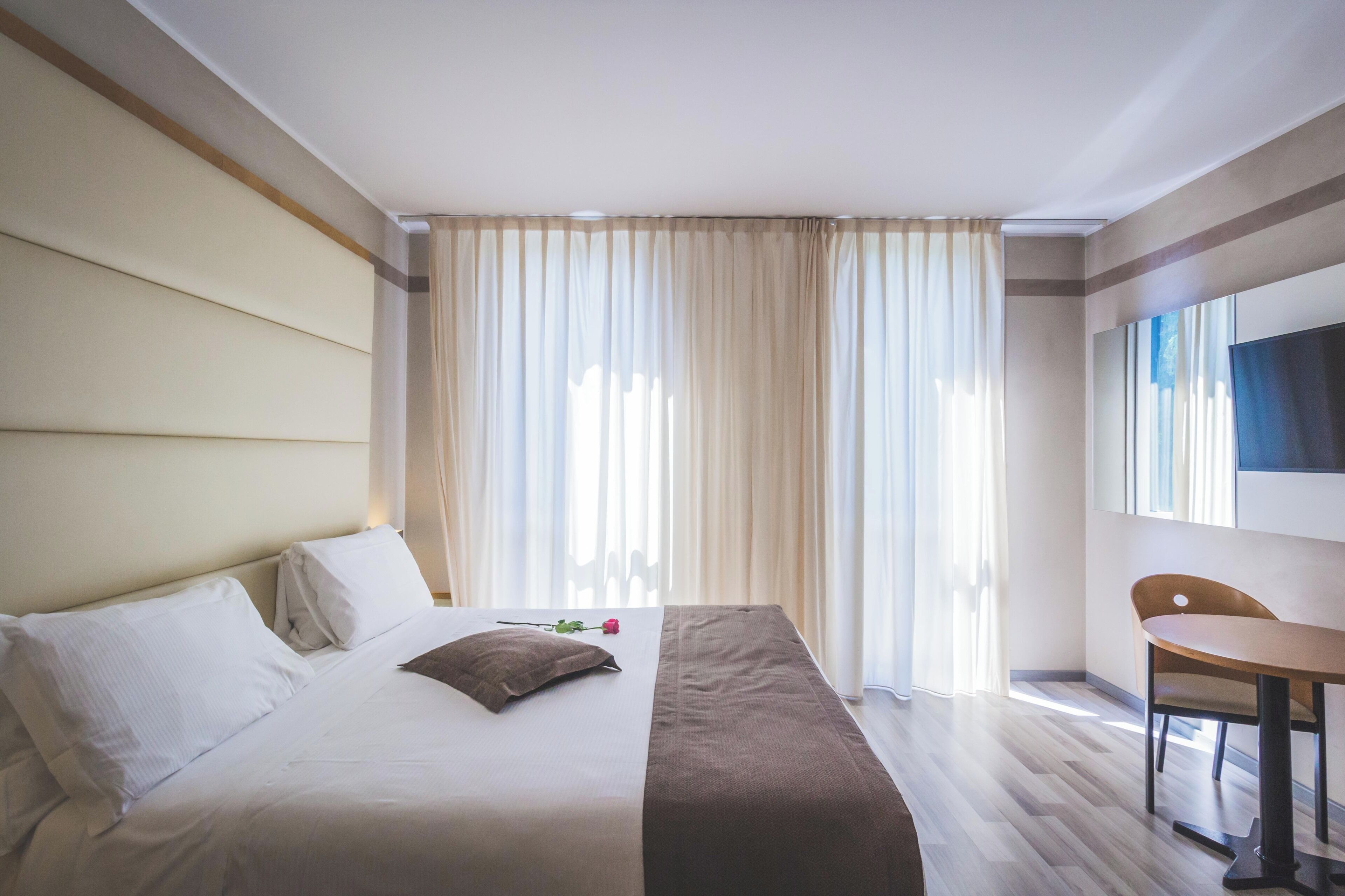 Ein Hotelzimmer mit einem großen Bett, einem Schreibtisch und einem an der Wand befestigten Fernseher.