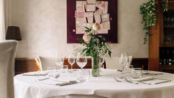 A dining table set with white tablecloth, wine glasses, and a vase with flowers.