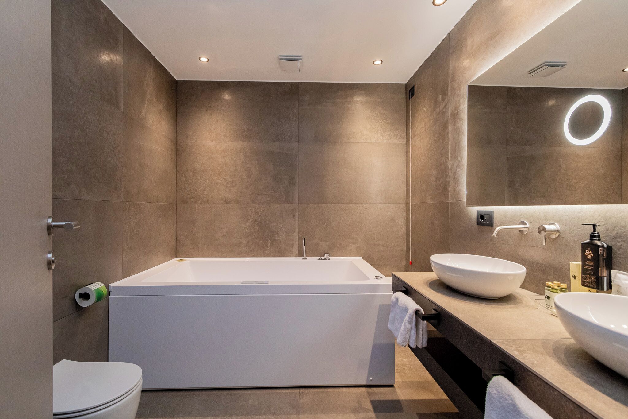 Une salle de bain moderne avec une grande baignoire, un miroir rond et un lavabo.