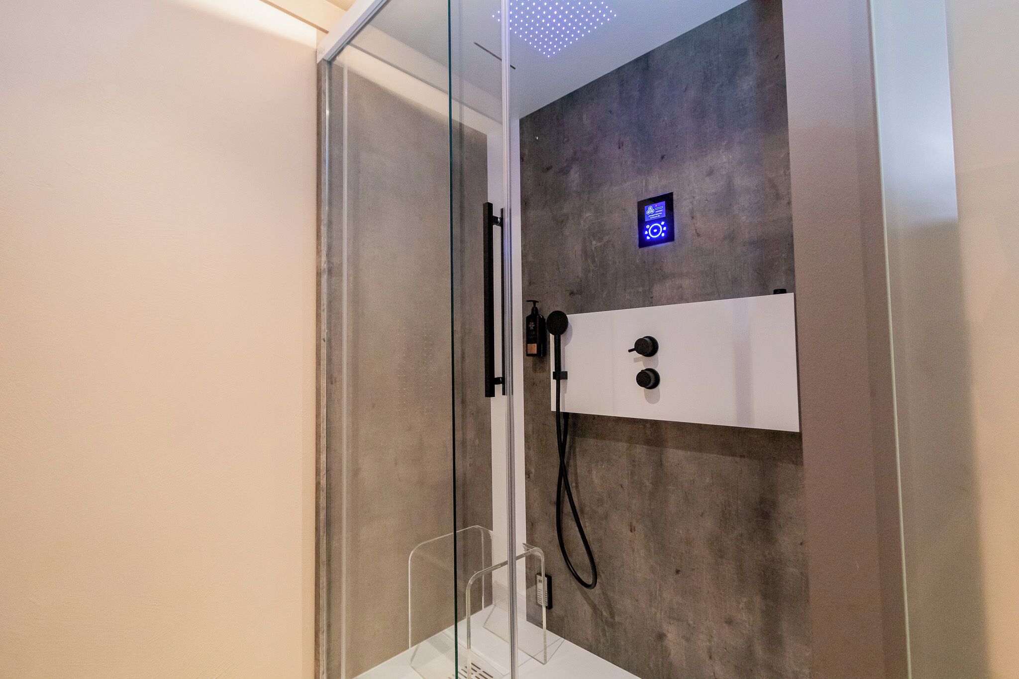 Un box de ducha moderno con panel de control y puerta de cristal.