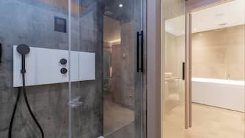 A modern bathroom with a glass-enclosed shower, a white vanity with a sink, and a large bathtub.