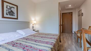 Une chambre d’hôtel avec un lit, une table de chevet, une lampe et un tableau encadré au mur.