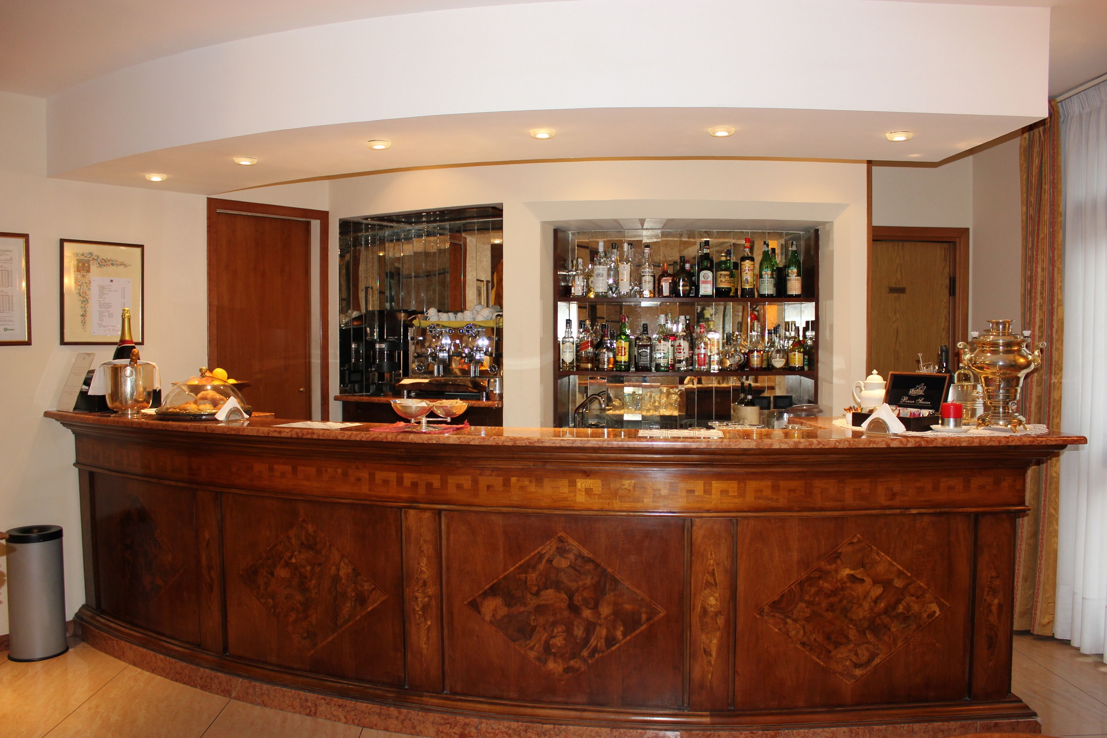 Una zona de bar con mostrador de madera, estantes con botellas y un cubo de basura.