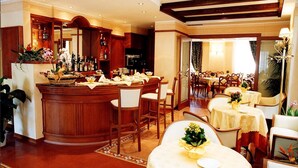 Een hotellobby met een bar, meerdere eettafels en stoelen.