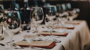 A table set with wine glasses, plates, and cutlery, indicating a dining area. - Kleos Hotel Milano by Kleos Group Collection (Milan)