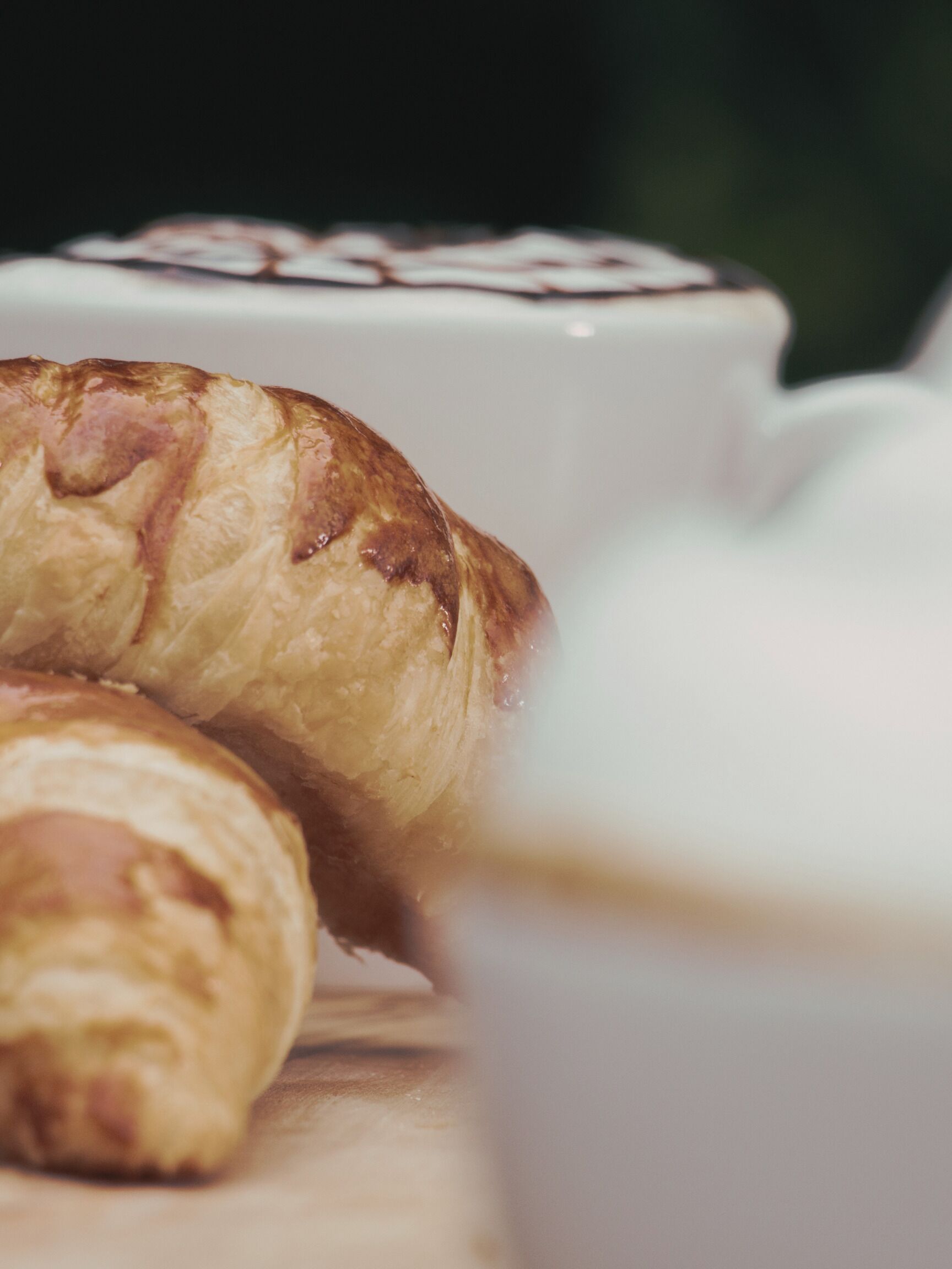 A croissant and a cup of coffee on a table.