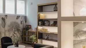 A modern living room with a sofa, coffee table, and shelves with decorative items. - Kleos Hotel Milano by Kleos Group Collection (Milan)
