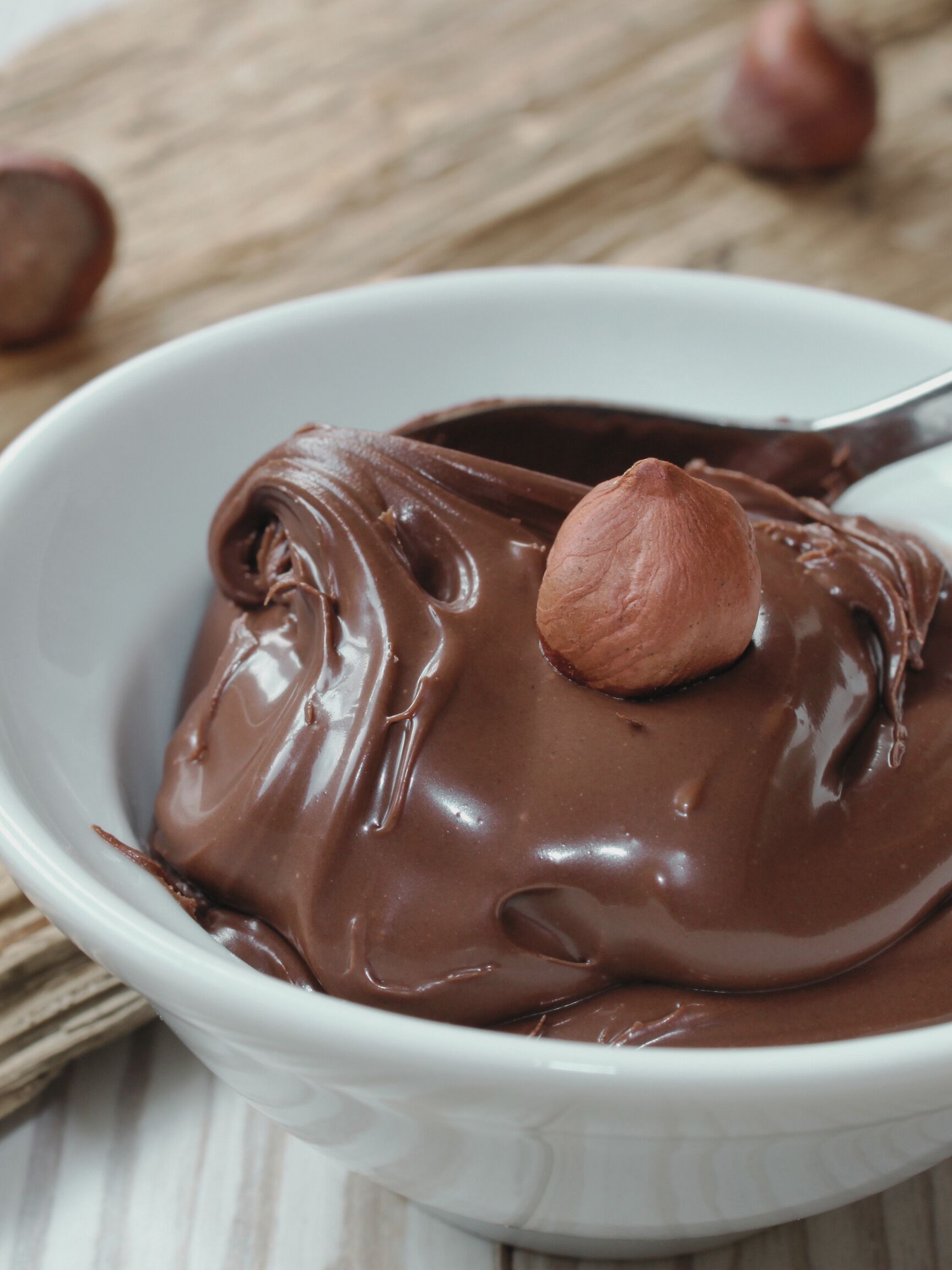 A bowl of chocolate mousse with a hazelnut on top.