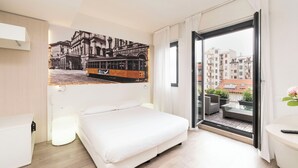 A hotel room with a bed, a large window with a view of buildings, a wall-mounted artwork of a tram, and a small balcony area. - Kleos Hotel Milano by Kleos Group Collection (Milan)