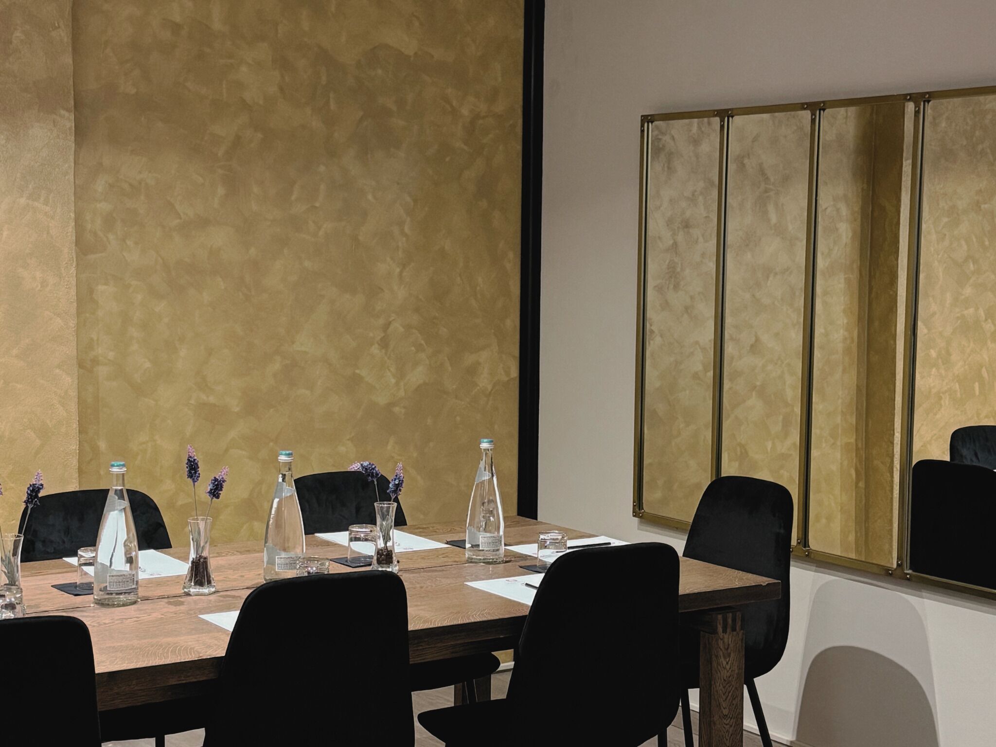 Une salle de conférence avec une longue table, des chaises noires et une grande fenêtre donnant sur un beau paysage.