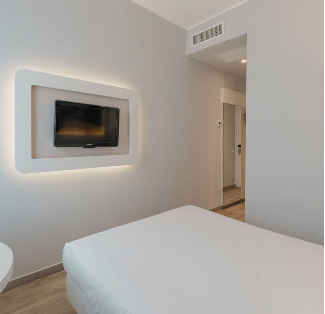 Une chambre d’h ôtel moderne avec un grand lit, un téléviseur fixé au mur et une salle de bain dotée d’un lavabo rond.