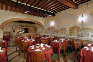 Comedor con mesas dispuestas para el servicio, una zona de bar y un mural con edificios en la pared.