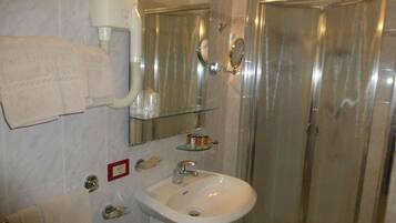 Une salle de bain avec une douche à parois de verre, un lavabo blanc et un miroir au-dessus.