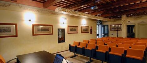 A conference room with a wooden ceiling, a projector, and a laptop on a table.