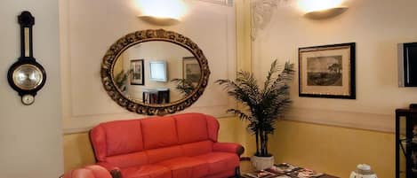 A living room with a red sofa, a wooden coffee table, and a large mirror on the wall.