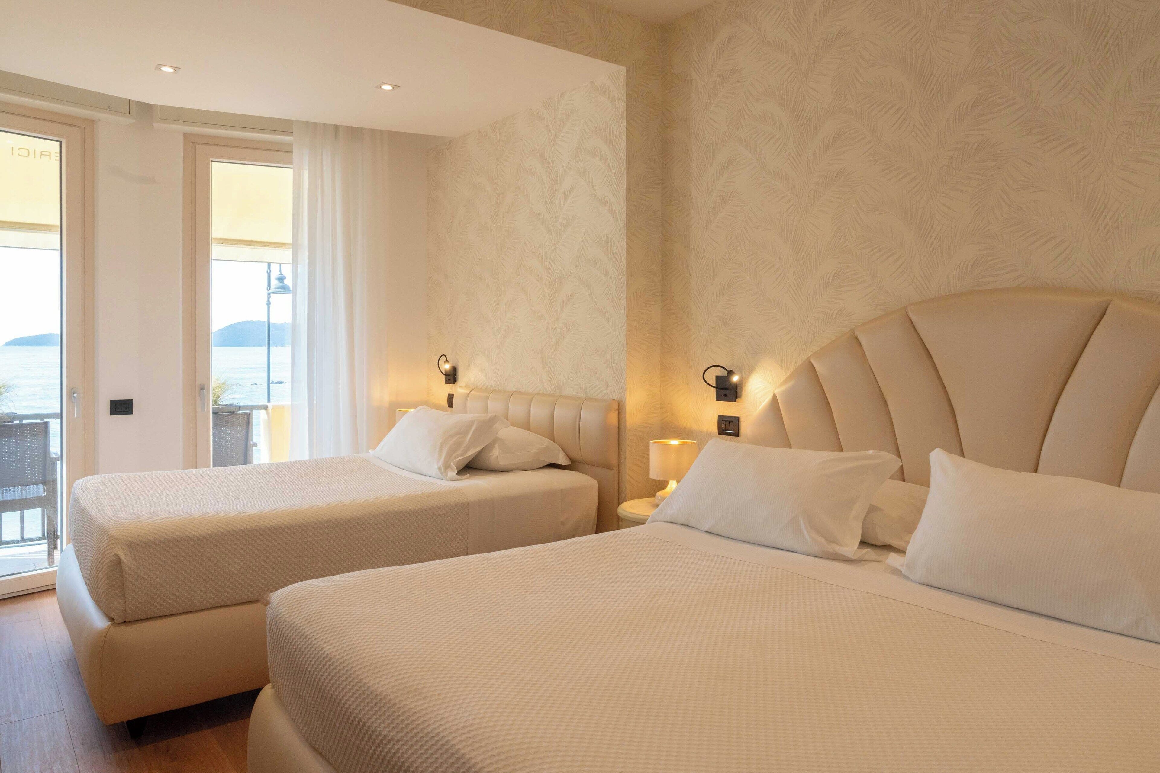 A hotel room with two beds, a balcony, and a view of the sea.