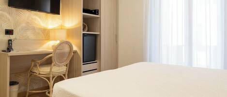 A bedroom with a bed, a desk with a chair, a television, and a wardrobe.