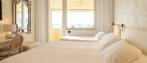 A hotel room with a large bed, a bedside table with a lamp, a chair, and a window with a view.