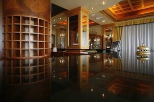 A spacious lobby with a polished floor, wooden columns, and a reception desk.