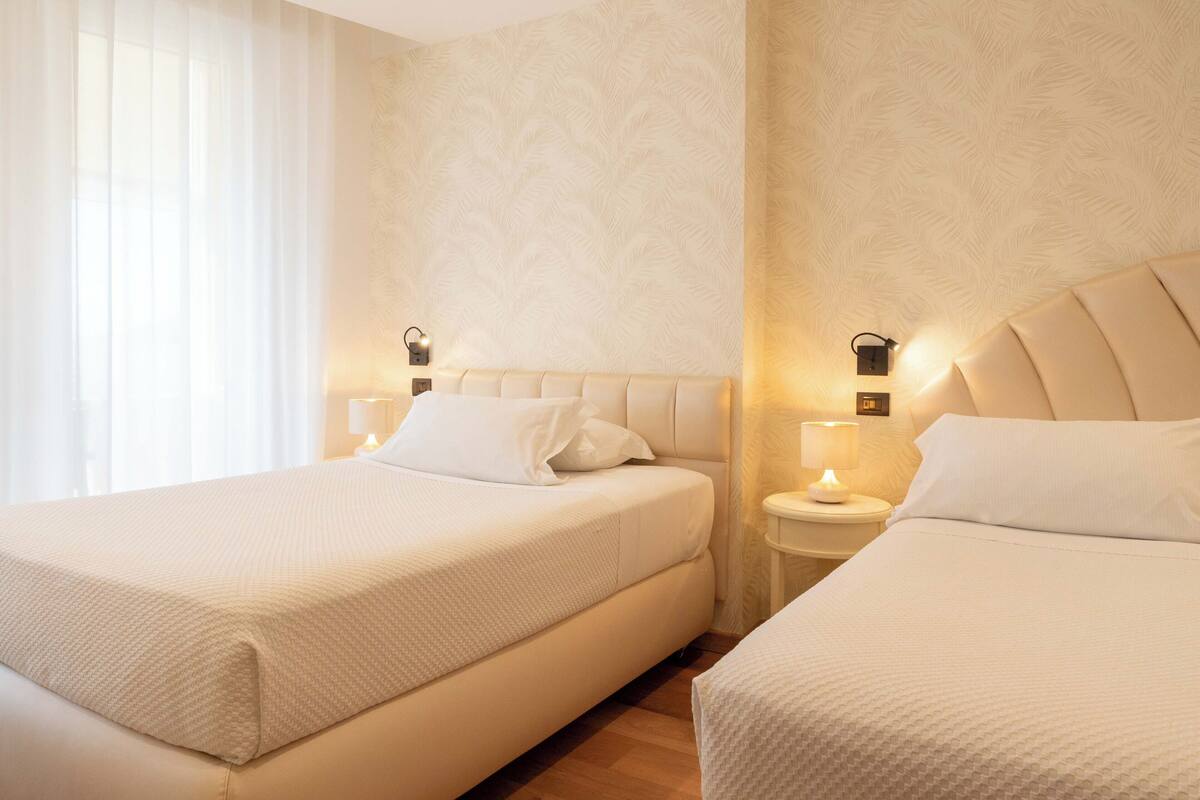 Ett hotellrum med två sängar, var och en med en sänggavel och sänglampor.