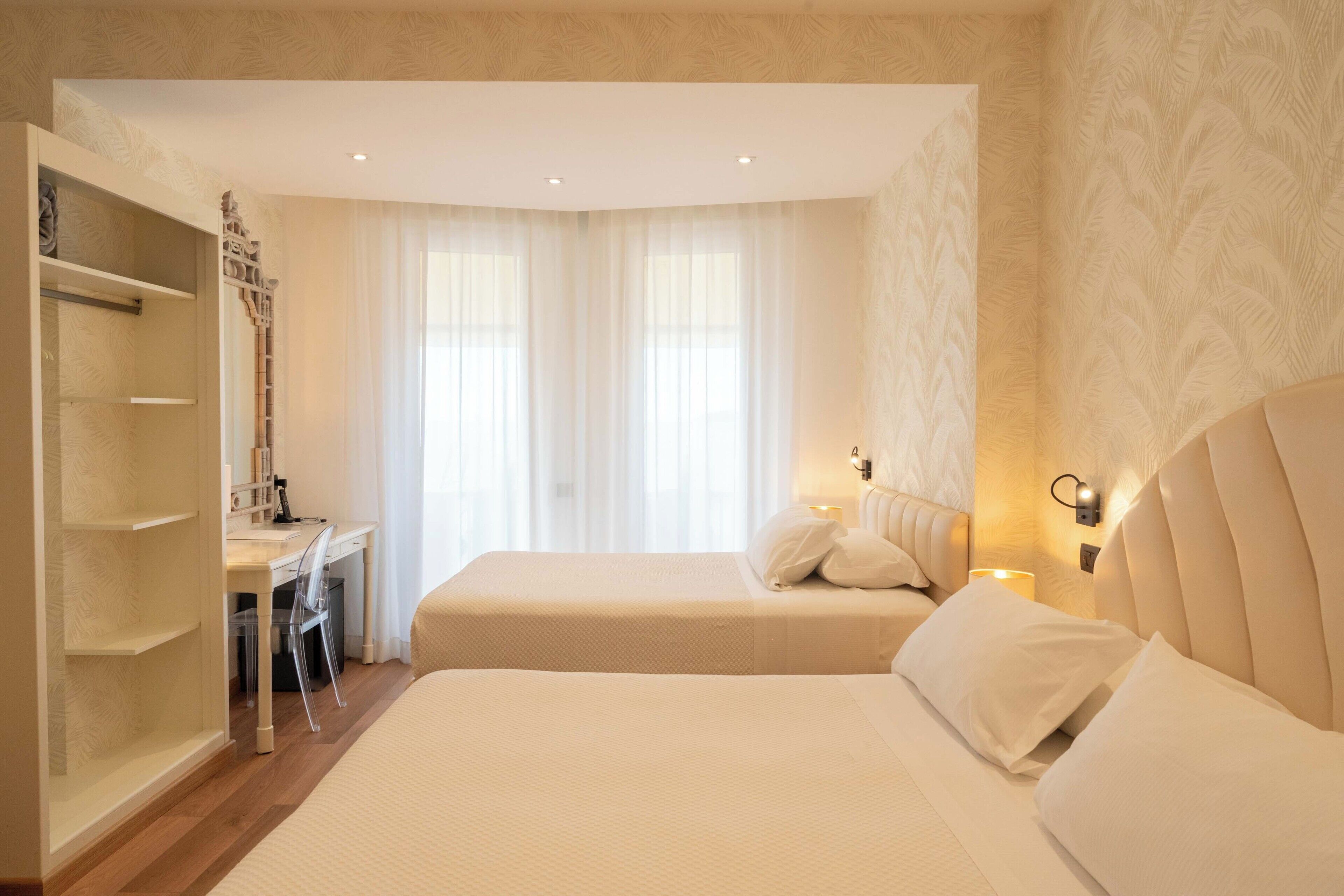 Una camera d'albergo con due letti, una scrivania e un armadio.